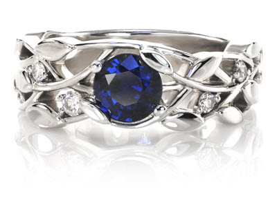 Blue sapphire engagement ring shown in floral setting with 5 smaller diamonds prong set in 14k White Gold.