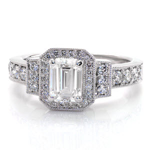 Three different sizes of mesmerizing micro pavé accent the band, side bars, and halo of this ring. The contrast between the faceted round side diamonds and the elegantly cascading steps of the emerald cut truly puts the focus on the center stone. Milgrain detail adds a soft texture to all edges.  