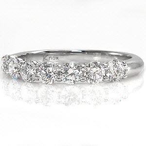 A contemporary band, this sleek seven stone design can easily be worn as a wedding ring or an anniversary band. The ring has a total weight of 0.65 carats of round brilliant cut diamonds in shared prong settings. This ring can be customized with different gemstones set in either platinum or any color of gold. 