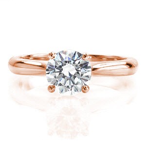Silk is a classic solitaire with a touch of flair. The contour of the band raises to a cathedral and is accented with pinched shoulders. A captivating 1.0 carat round brilliant diamond is held in a four prong basket slightly above the mounting. The sleek polished finish highlights the luster of the diamond. 