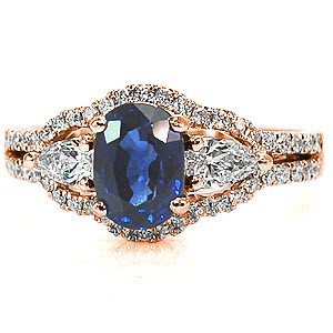 A unique, luscious design, the focus of this piece is all in the rich color of the center stone. On either side is a dazzling pear cut diamond which elegantly compliment the oval cut of the center sapphire. The band splits into two rows of micro pavé hugging the curves of the three center stones.