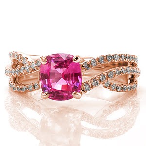 Adriana Sophia features a 1.84 carat cushion cut pink sapphire in a four prong setting. The vibrant pink hue is a striking pop of color in the shining 14k white gold setting. The micro pavé diamonds line the three woven bands to add brilliance and fire to the sapphire center.