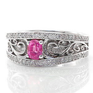 The Arabella sapphire ring features a 0.40 carat bright pink oval sapphire. Crafted in 14k white gold, high polished curvacious scrolls accent the hand stippling detail. The band edges are finished in milgrain and micro pavé diamonds. The wide vintage inspired band gradually tapers down for a comfortable fit.