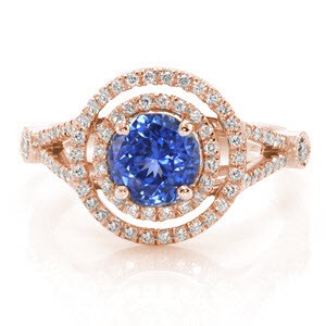 Indigo Ice radiates with sparkle from the adornment of round brilliant diamonds. The dazzling blue sapphire is encircled in a double halo for a magnificent sight. The split shank is decorated in diamonds and detailed with a bezel set round stone at the bottom of the tapper. 