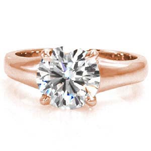 This dramatic solitaire focuses on a 1.50 carat round brilliant cut diamond. The classic four prong setting secures the stone onto the wide, flared band. The luster of the high polished metal is an elegant contrast to the vibrant prism of colors from the center stone. 