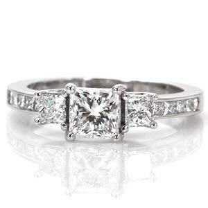 The Princess Beauty reflects classic styling of a three stone setting with an added flair of a trellis prong basket. The 0.75 princess cut center diamond is the center of attention with its sharp lines and geometric shape. Crafted in 18k white gold, the band is channel set with princess cut diamonds.