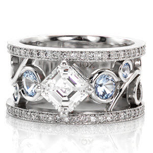 This unique wedding band features a 1.0 carat asscher cut center stone kite set within a four prong crown. The hand made filigree elements creates an alluring pattern that flows around six blue sapphires. The design is flanked by two rows of micro pavé diamonds for a sparkling finishing touch.