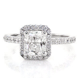 The Classic Cushion Halo dazzles with a unique, clipped corner, square halo around a 1.25 carat cushion cut center diamond. The halo and band are stunningly detailed with micro pavé which will vibrantly dance in any light. There is also a row of surprise diamonds underneath each side of the halo.