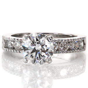 The classic 1.30 carat round brilliant center diamond rests high above the band in a sleek 4-prong setting. Large channel set side diamonds line the band to add sparkle to the brilliant white gold metal. Milgrain texture forms the outside edge of the engagement ring and matching band for added detail.