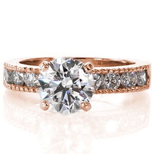 The classic 1.30 carat round brilliant center diamond rests high above the band in a sleek 4-prong setting. Large channel set side diamonds line the band to add sparkle to the brilliant white gold metal. Milgrain texture forms the outside edge of the engagement ring and matching band for added detail.