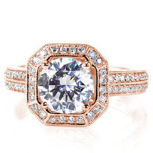 A breathtaking design with tantalizing details the 1.50 carat round brilliant cut center diamond is surrounded by a square, clipped-corner micro pavé halo and supported by a double-row micro pavé band. The basket of the center and the inside of the band are adorned with alluring hand made filigree.