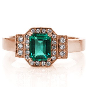 The vivid green emerald is surrounded in a halo of diamonds that mimics the shape of the emerald cut center. The halo and parallel rows of three diamonds are outlined in milgrain detail to contrast the smooth lines of the polished band. The 14k white gold finish compliments the bold color of the gemstone.   