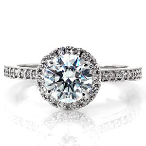 This charming engagement ring features a 1.00 carat round brilliant cut center diamond. The halo and band of the ring are detailed with vibrant micro pavé diamonds. The center setting of the ring is raised to allow for a traditional wedding band to sit perfectly next to it.