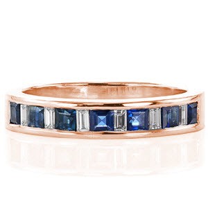 This ring mesmerizes with its blue sapphire princess cut stones. The sapphires alternate with baguette cut diamonds which tie beautifully with the 14k white gold. The straight lines are carried throughout the design of the band for simple elegance. The cool tone of the stones and metal make for a sticking statement. 