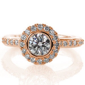 This dazzling design will twinkle and dance in any light. The bead-set diamonds on the band and halo are a perfect accent for the bezel set 0.60 carat round brilliant center stone. The luster of the high polished metal adds to the radiance of this beautiful piece.