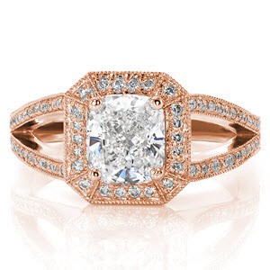 The luxurious square shaped halo with clipped corners is intricately fashioned with micro pavé diamonds. A reverse taper of the band curves into a split shank to the side of the halo. The hand-formed platinum filigree adds a decorative statement to this contemporary cushion cut design.  