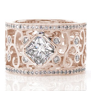 This custom wide band makes a statement with a 1.00 carat radiant cut center stone. The high polished metal of the bezel setting compliments the curls of the band. There are round diamonds bezel set among the large filigree. The edges of the ring are completed with rows of micro pavé. 