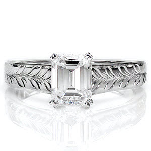 This traditional ring includes a lovely long faceted emerald cut 1.0 carat center diamond held in a four prong setting. The linear quality of the center stone is mimicked in the straight shank with comfort fit interior. The top face contains bright cut hand engraving in a modified wheat pattern.