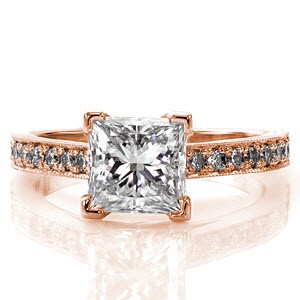 The luxurious 1.25 carat princess cut diamond fashioned high above its setting is a breathtaking sight. The row of bead set diamonds raises to a cathedral to compliment the impressive height of the center stone. The milgrain edge adds a striking texture to this marvelous design.  