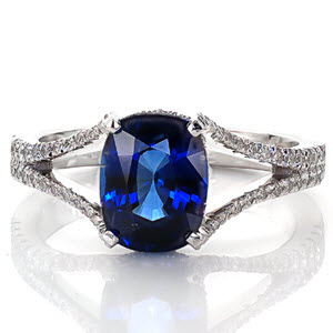 Our Royal Blue design emits regal elegance with rich velvety blue tones. The center stone is a beautiful 2.0 carat cushion cut sapphire set in a four prong setting with micro pavé diamond under bezel. The diamonds continue along the split-shank band design that is gracefully frames the sapphire. 