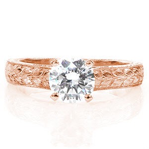 Lucent is a tantalizing nature inspired design crowned with a 1.00 carat round brilliant cut solitaire diamond. The wider band curves gracefully up to meet the cathedral setting of the center stone. Both sides and the top of the band are all exquisitely detailed with hand engraved leaf designs. 