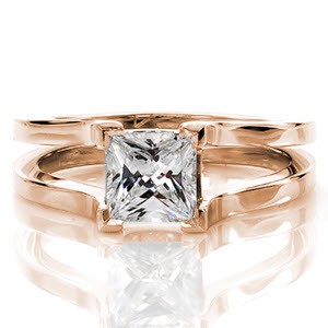 The Cathedral design has four chevron prongs that frame a 1.00 carat princess cut diamond solitaire. The shank swoops upwards towards the stone showcasing the side view of the diamond. The crisp split shank band in 14k white gold creates a modern look for this contemporary design.