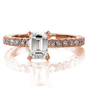 The long parallel facets of the emerald cut are an elegant contrast to the brilliant micro pavé stones. Held in a four prong setting the emerald diamond takes the center of attention sitting high above the band. Round brilliant diamonds line the ring for sparkle and fire.