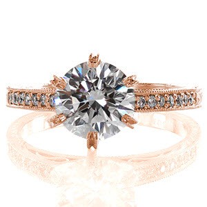 This antique inspired ring features a thin band detailed with hand engraved designs and hand formed filigree curls. The top of the band also features a row of micro pavé as an accent to the 1.50 carat round brilliant cut center diamond. The stone is held in an elevated setting with six prongs.