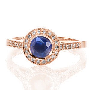The Filigree Enchantment design has a classic full bezel surrounding the 0.60 carat round natural blue sapphire. Adding to the divine design is a full circle halo of micro pavé diamonds, hand wrought filigree scrolls and two full bezel set surprise diamonds.