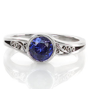 The purplish blue 1.00 carat sapphire is encircled in a full bezel to emphasize the mysterious color of the center gemstone. The open split shank is decorated with hand-formed filigree for a picturesque view. The high polish of the edges is a sleek finish to this sophisticated design.       