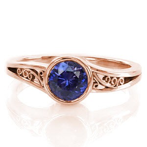 The purplish blue 1.00 carat sapphire is encircled in a full bezel to emphasize the mysterious color of the center gemstone. The open split shank is decorated with hand-formed filigree for a picturesque view. The high polish of the edges is a sleek finish to this sophisticated design.       