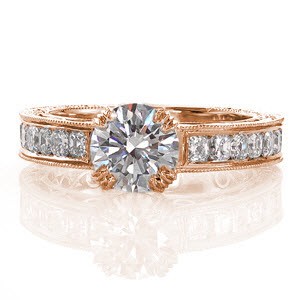 This luxurious design focuses on the 1.00 carat round brilliant cut center diamond. the decorative double prongs and the side faces of the band are adorned with micro pavé. The side profile and inside of the band feature graceful, hand formed filigree curls. The top of the band displays channel set asscher cuts.