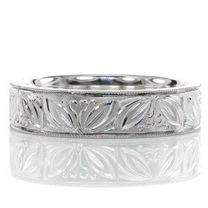 This captivating wedding band is custom designed in 14k white gold. The hand engraved design on the ring is a pattern of leaves and curled vines. This vintage inspired eternity band is edged with milgrain texture which adds a refined finish to the piece.