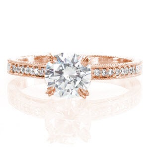 Beautiful in and language, the Bella design presents a 1.00 carat round brilliant cut center diamond with milgrain finished prongs and edges. The 14k white gold micro pavé diamond band and scrolled hand engraving mimic the curves of the hand wrought filigree and surprise diamonds.