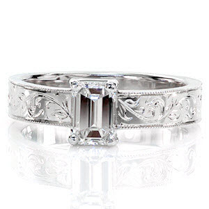 Lorrie features a sophisticated 0.75 carat emerald cut diamond. The long rectangular facets descend towards the center of the stone to accentuate its luster and whiteness. The extravagant pattern of the hand-carved engraving and the textured milgrain edges possess a vintage charm.  