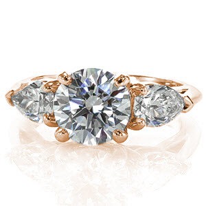 The elegant contour of the XOXO is created with the two pear cut diamonds that taper away from the 1.50 carat round brilliant center diamond. The simple setting puts all the focus on the stunning diamonds. The band tapers in to meet the points of each pear cut side stone.