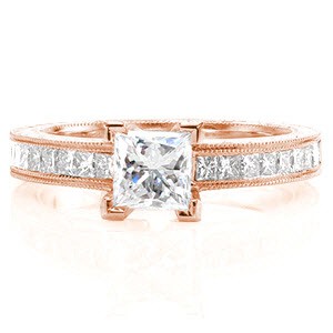 Lucia is a charming, unique design featuring a 0.75 carat princess cut center diamond. Each side is framed by channel set princess cuts on the top of the band. The edges of the band are accented with milgrain texture for a refined finish and the sides of the band are detailed with hand engraving.