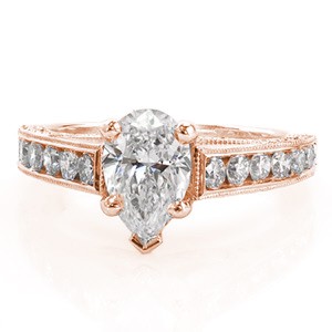 The alluring shape of the 0.80 carat pear cut center diamond is highlighted by the cathedral setting. The top of the band features round channel set diamonds while the side profile reveals an elegant arch of micro pavé. The side stones are all edged with milgrain for a refined finish.
