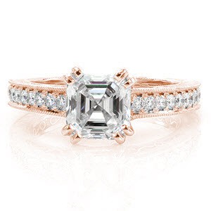 A 1.20 carat asscher cut diamond is held in place in a claw prong with micro pavé diamond detail along the side. The diamonds continue along the sides of the band and are paired with hand engraved detail. Filigree adorns two pockets on the sides of the band as well as the inside of the ring.   