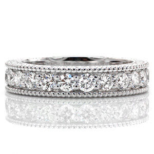 This classic band is made elegant by the engraved pattern on the side faces of the ring. The diamonds securely fashioned with shared bead-set prongs add up to 1.50 total carat weight. The edges of the design are refined with beaded milgrain texture that beautifully accents the prongs of the stones. 