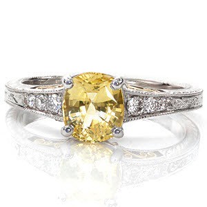 This mesmerizing design is a two-tone 14k yellow and white gold combination. The center stone is a 1.00 carat cushion cut yellow sapphire in a tapered white gold band. Micro pavé diamonds accent the center stone. Hand engraving and yellow gold filigree curls add the perfect compliment.