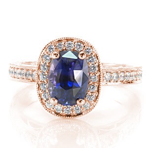 This sumptuous design uses little details to create an intricate piece. The luscious 1.50 carat cushion cut sapphire is a unique blue violet color that captures the eye. There are micro pavé diamonds set on the halo, band, and underneath the center setting. Hand wrought filigree and engraving complete the look.
