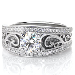 Blending the fascinating design of hand formed filigree with the function of a low profile style is found in Arabella. The .70 carat round brilliant cut diamond is set between graceful scrolls and unique hand stippling. Two rows of bright cut and bead set diamonds frame this custom masterpiece.