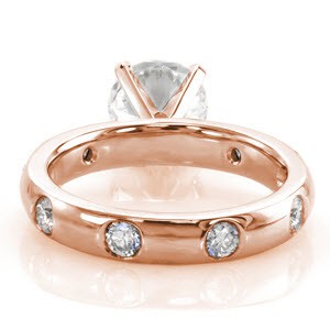 Toronto contemporary custom rose gold engagement ring with a round diamond center held by four prongs and a band with staggered flush set round diamonds.