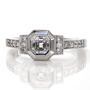 This design is inspired by the art deco style. The 0.75 carat asscher cut center stone is framed by a wide bezel which has been given a high polish to mimic the cascading, step cut facets of the diamond. The two bars to either side of center and the band are detailed with micro pavé and milgrain edging.