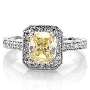 A stunning 1.0 carat cushion cut fancy yellow diamond takes center stage in this vintage inspired ring. micro pavé diamonds adorn the clipped corner halo. Decorative diamond and crescent shapes enhance the under bezel. Filigree, milgrain and micro pavé diamonds accentuate the band design. 