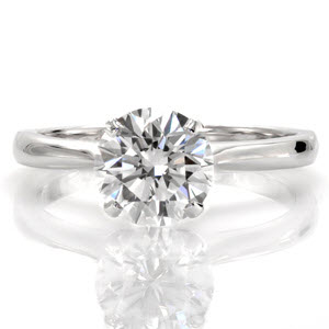 Filiano is a classic solitaire setting with a touch of flair. The narrow band arches to a point for a stylistically pleasing design element. The reverse V-shaped prongs elegantly display a 1.25 carat round brilliant diamond. The luster of the high polished band compliments the radiance of the center stone.    