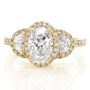 Unique yellow gold halo engagement ring in Portland. This stunning design is a three-stone setting with a halo around each large diamond. The thin diamond band adds focus to the center. Delicately hand crafted filigree curls adorn the basket under the halos.