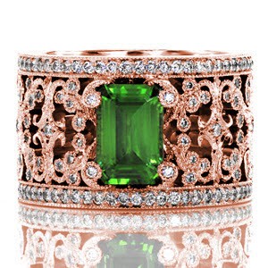 Intricate pierced scrolls created in 14k white gold and adorned with bead set diamonds. The Britty design showcases the emerald cut green gem stone with distinction by four diamond capped prongs. Two rails of shared prong round diamonds are finished with hand applied milgrain on our Knox Signature heirloom band.