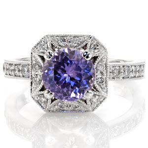 The Lotus Sapphire design is elegantly crafted in 14k white gold and presents a rich, violet round cut natural sapphire. Elements of the ring include detailed prongs, hand applied milgrain and bright-cut bead-set diamonds. The square beveled edge halo is joined by a band of round diamonds.